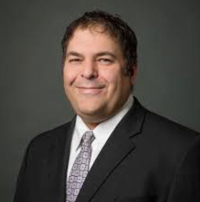 A man in a suit and tie smiles for the camera.