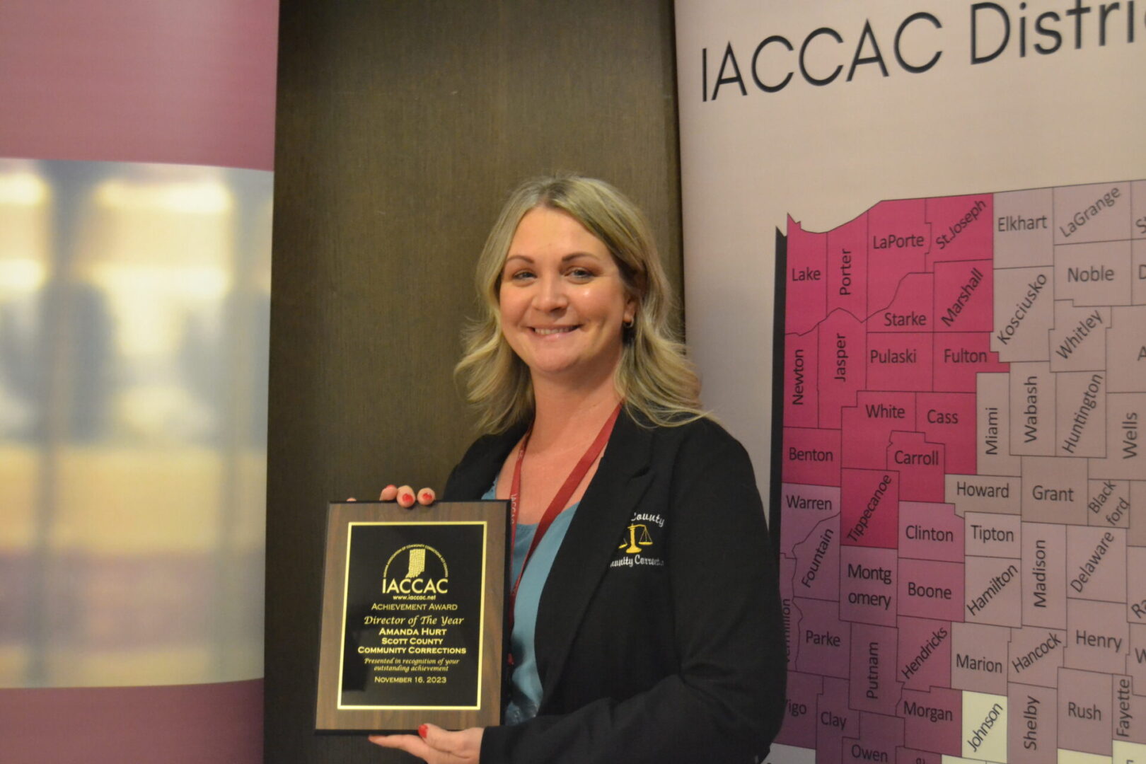 A woman holding an award in front of a sign that says jacac district.