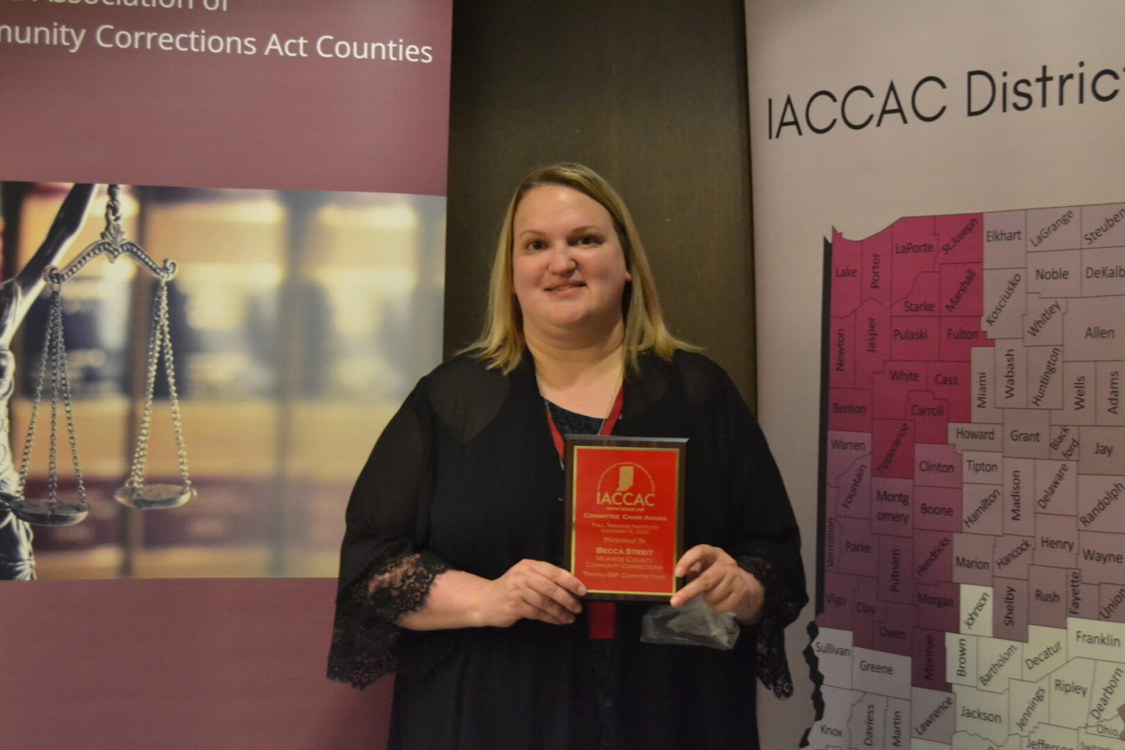 A woman holding an award in front of a banner.