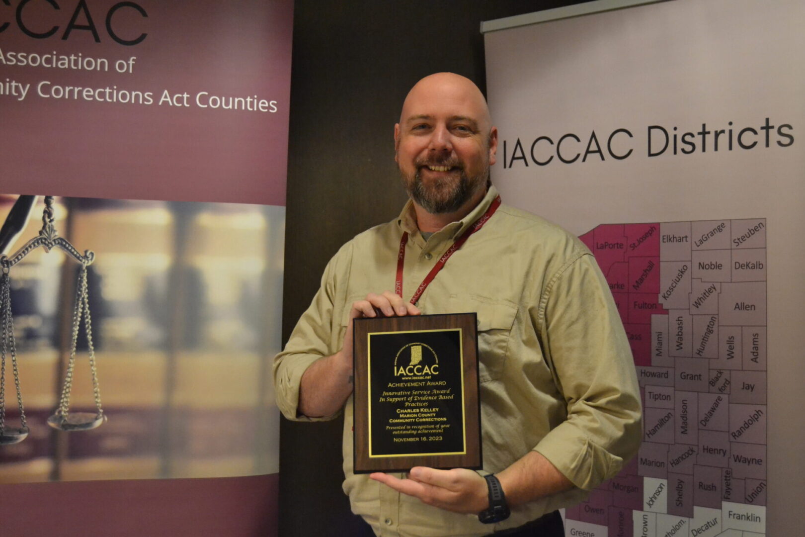 A man holding an award in front of a banner.