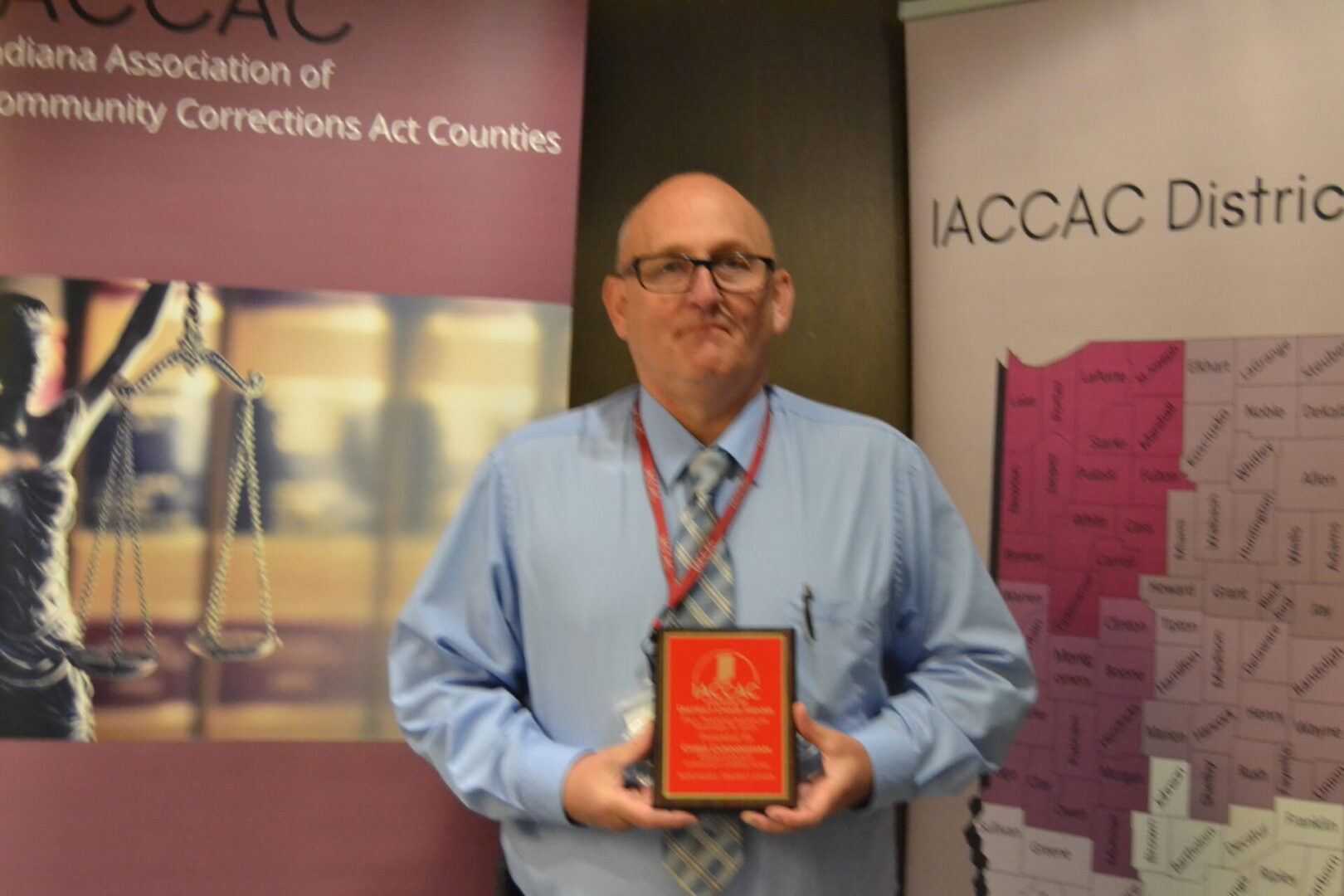 A man holding an award in front of a banner.