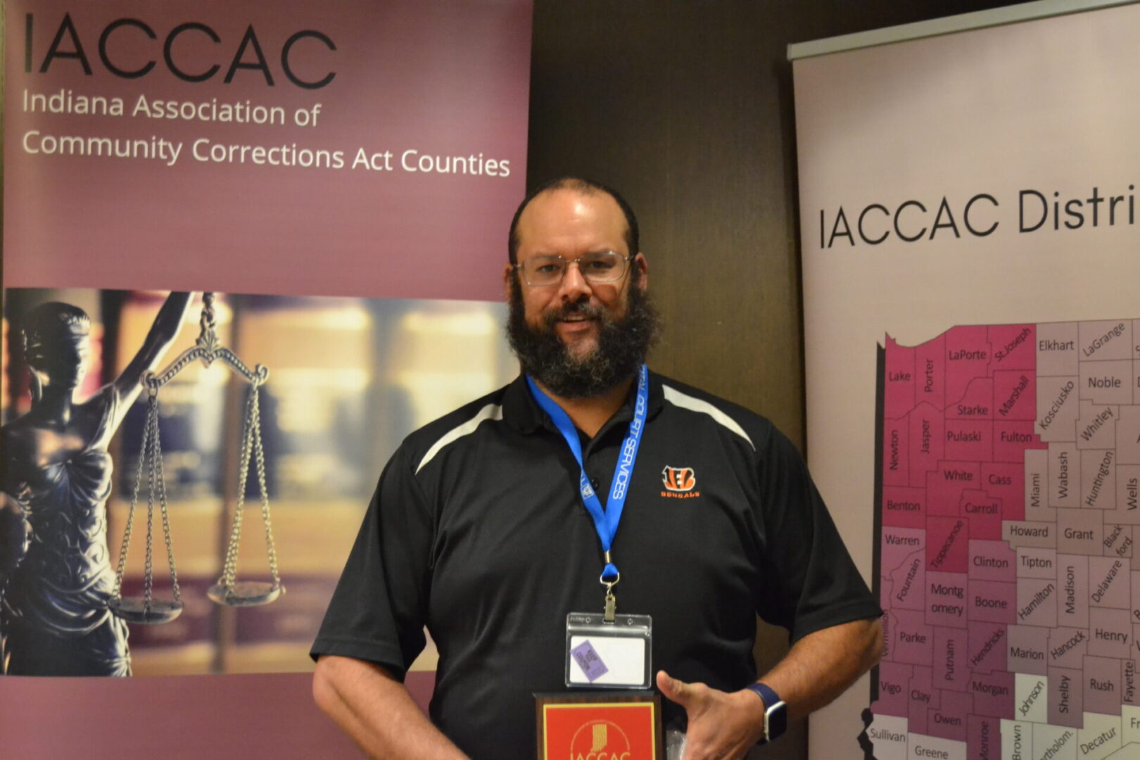 A man holding an award in front of a banner.