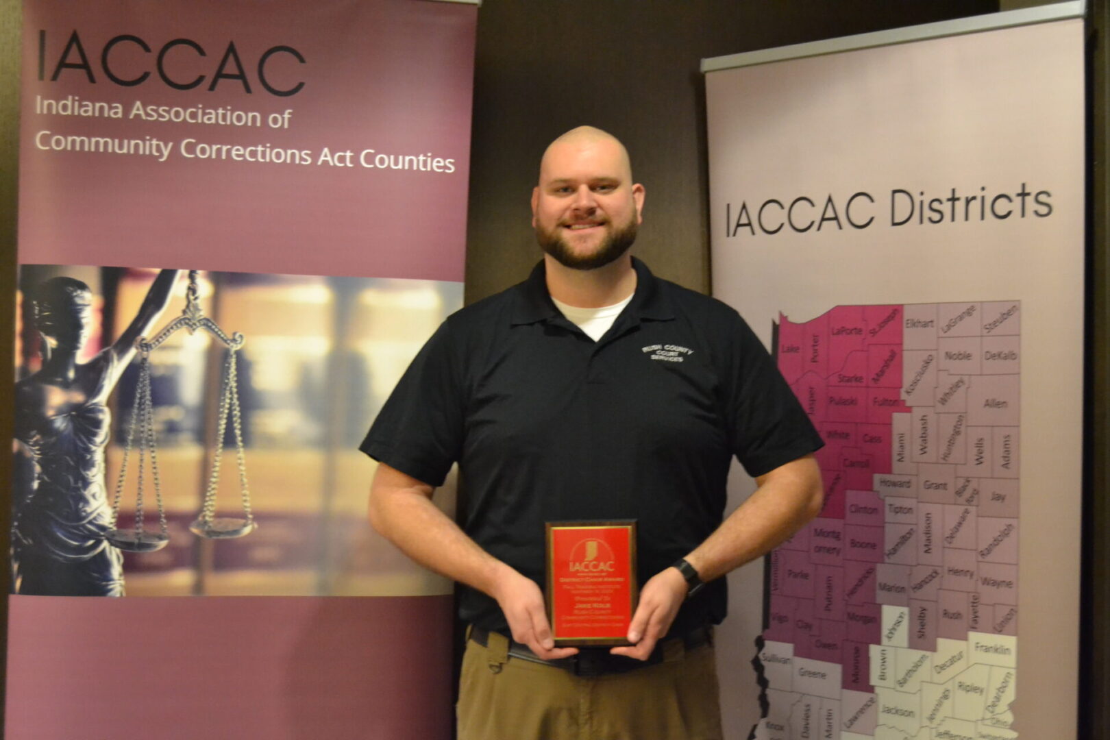 A man holding an award in front of a banner.