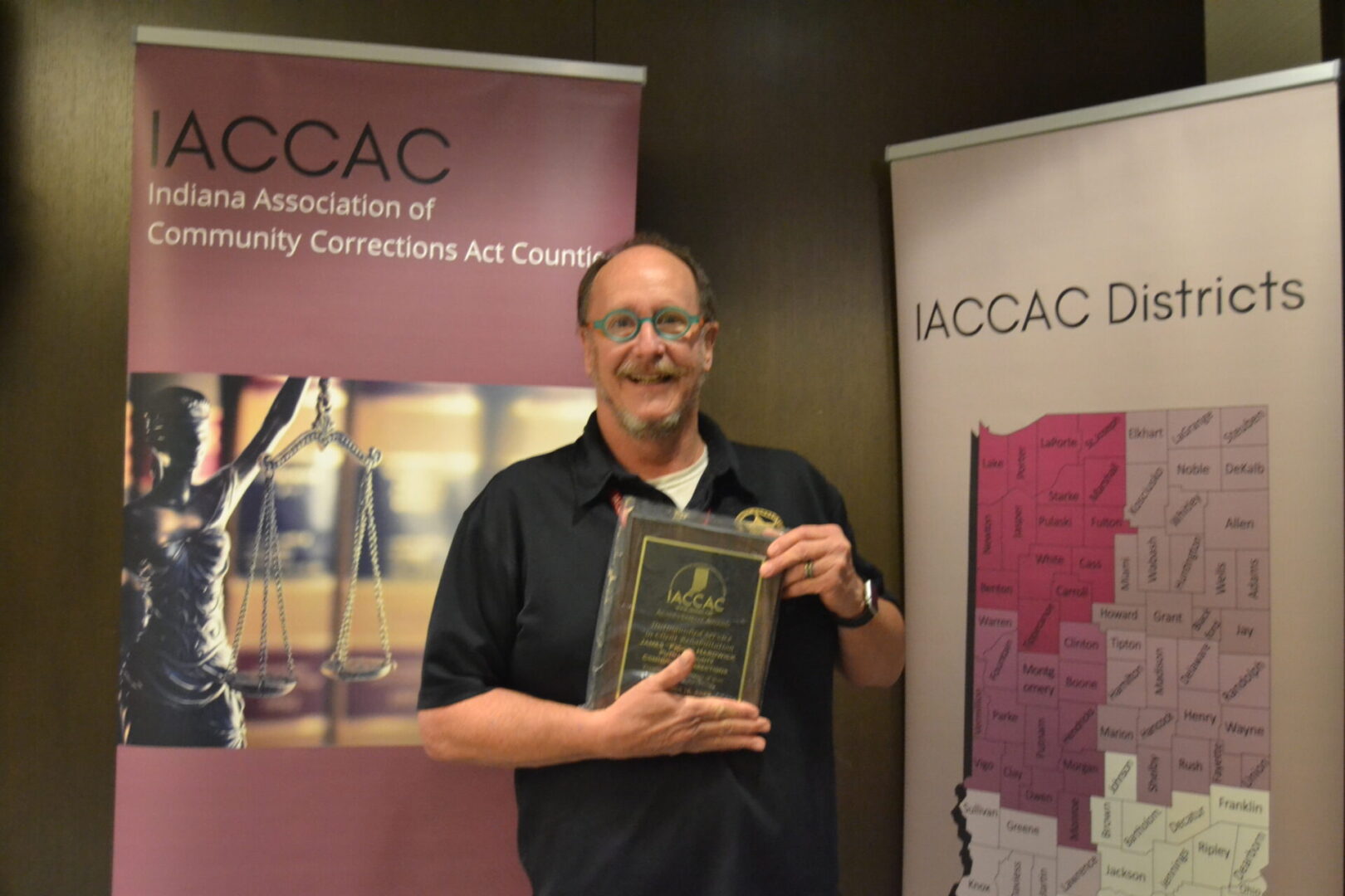 A man holding an award in front of a banner.