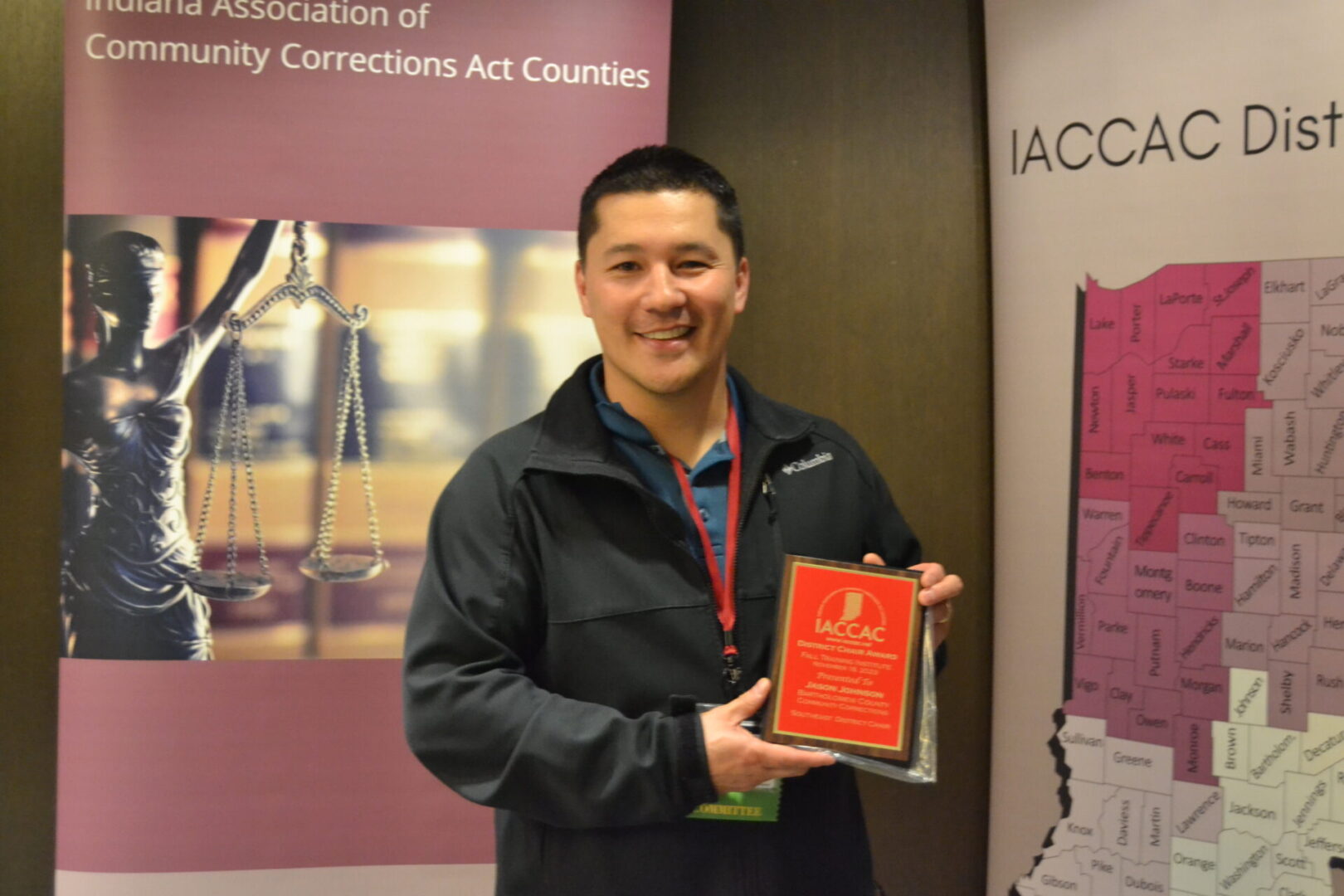 A man holding an award in front of a poster.