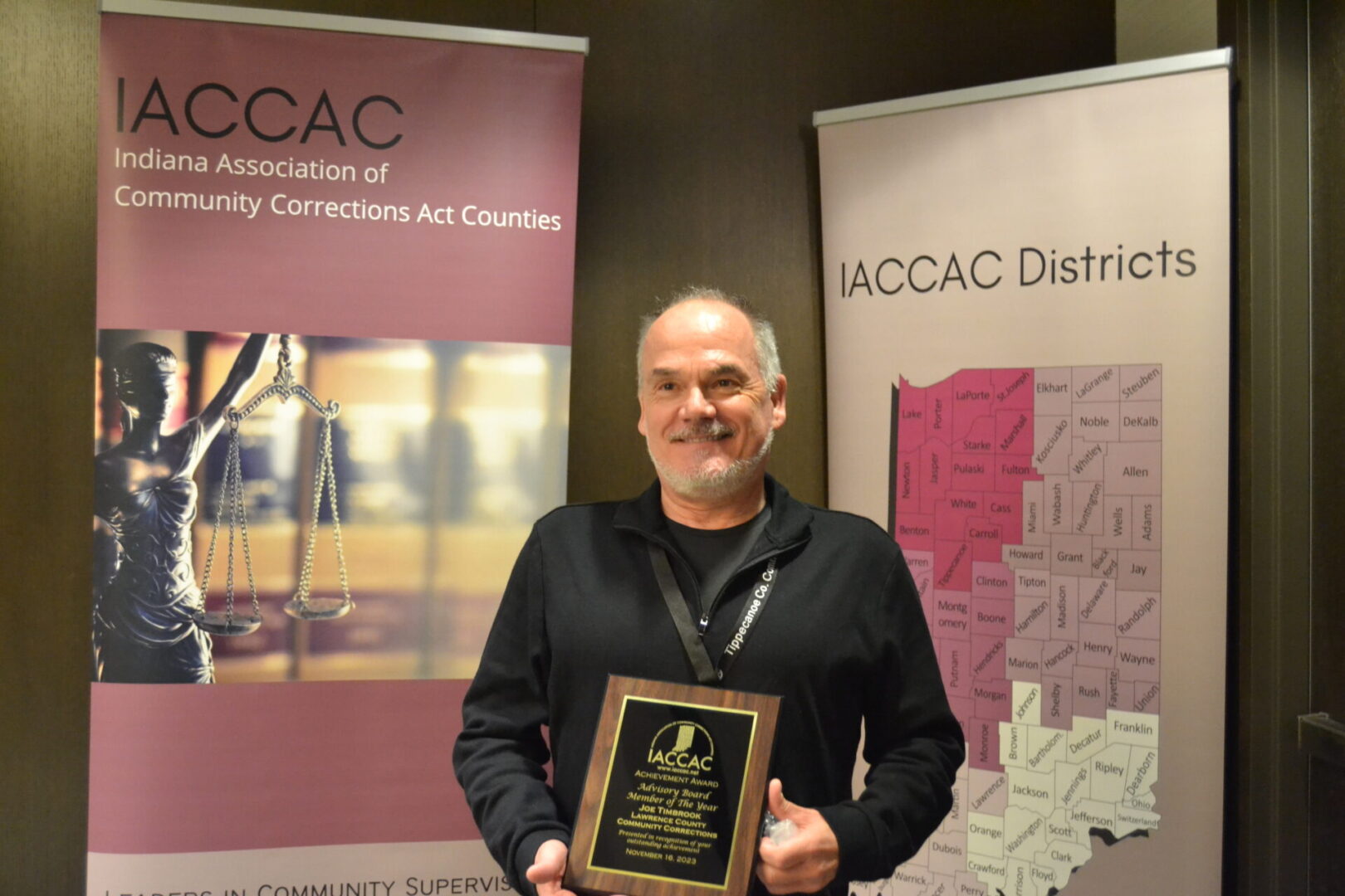 A man holding an award in front of a banner.