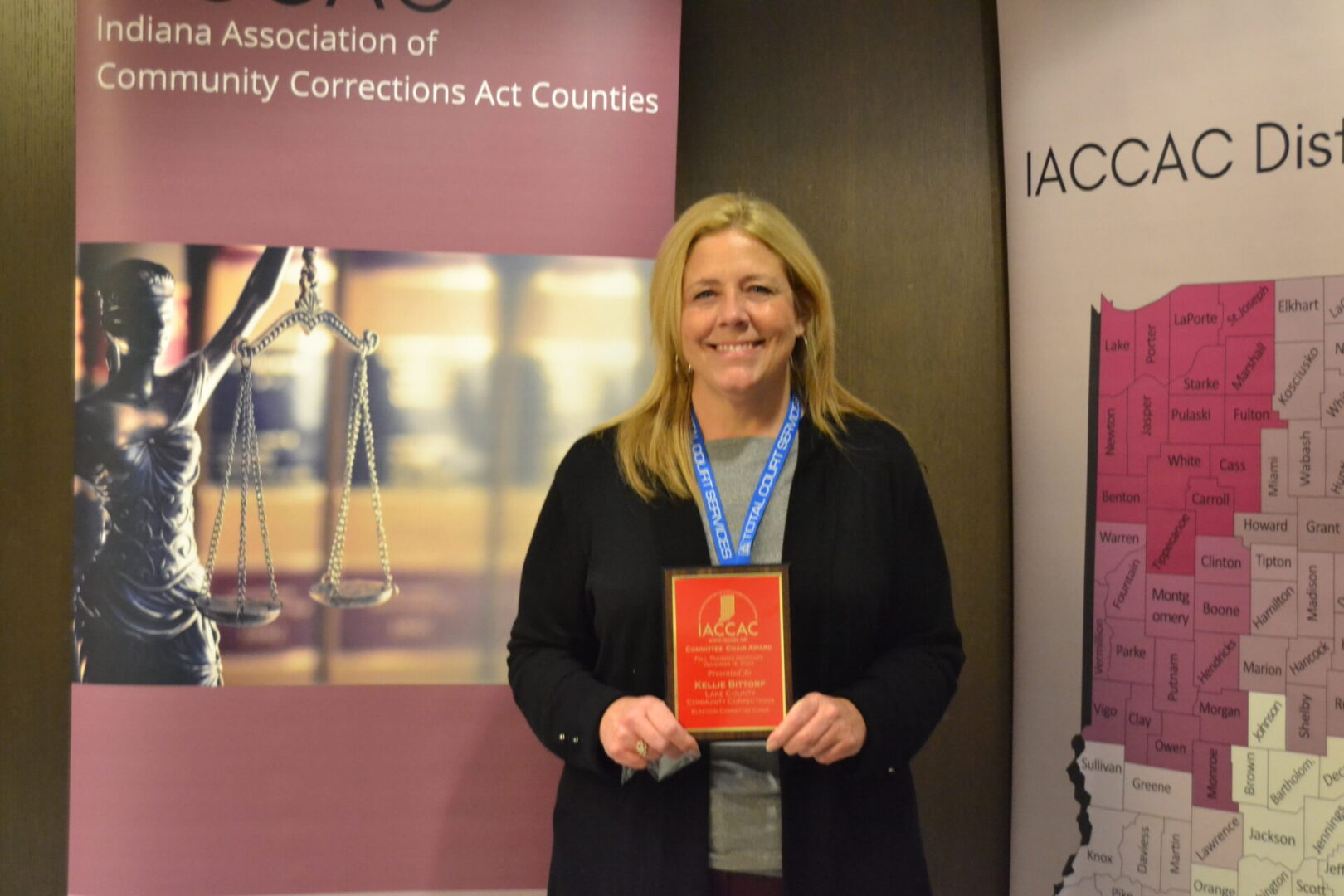 A woman holding an award in front of a banner.