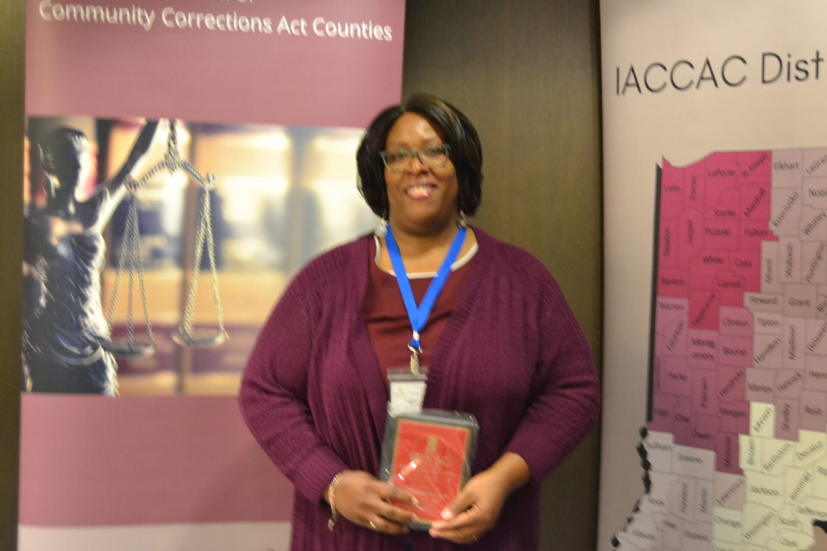 A woman holding an award in front of a banner.