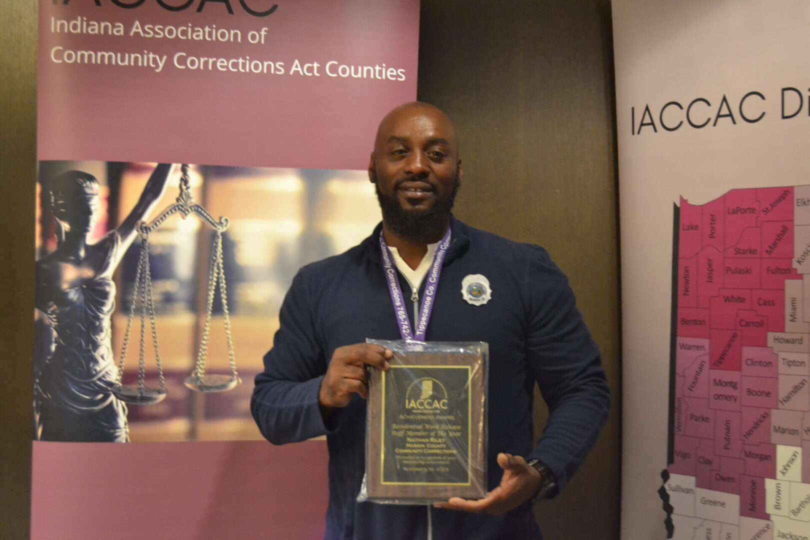 A man holding an award in front of a banner.