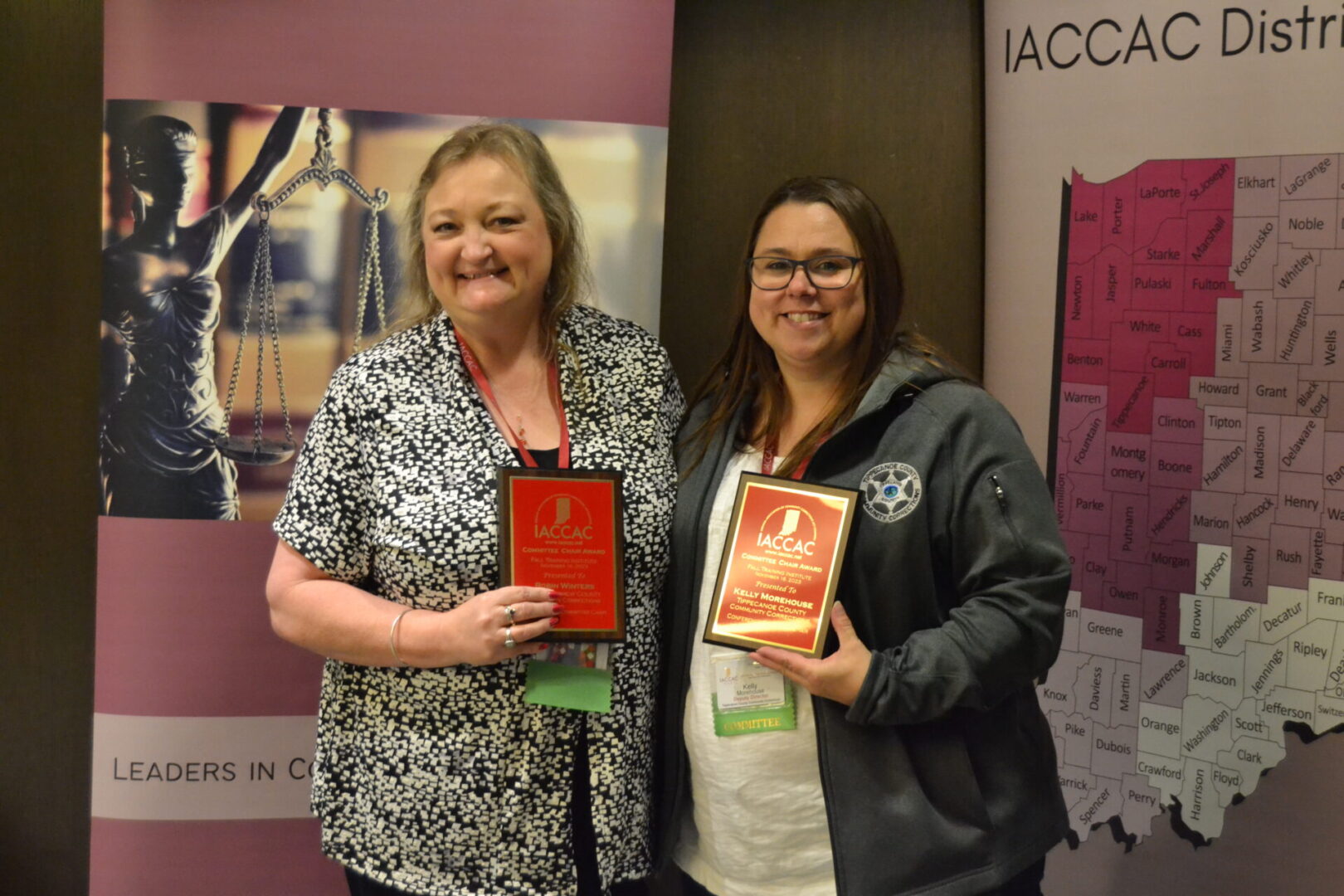 Two women standing next to each other holding awards.