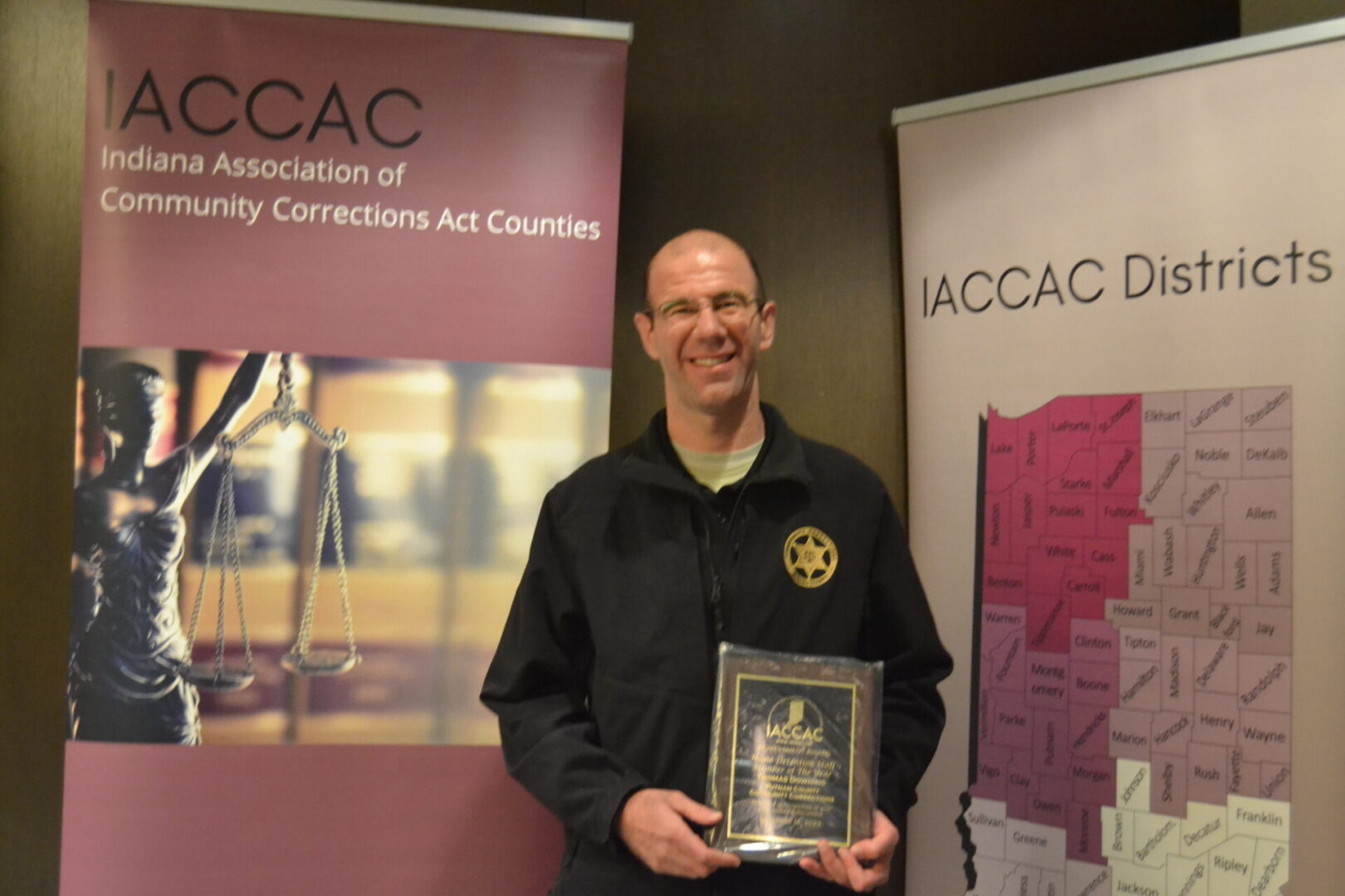 A man holding an award in front of a banner.